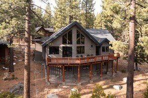 A cabin with a deck, surrounded by trees.