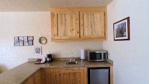 A compact kitchen with wooden cabinets, a microwave, a sink, and a dishwasher.