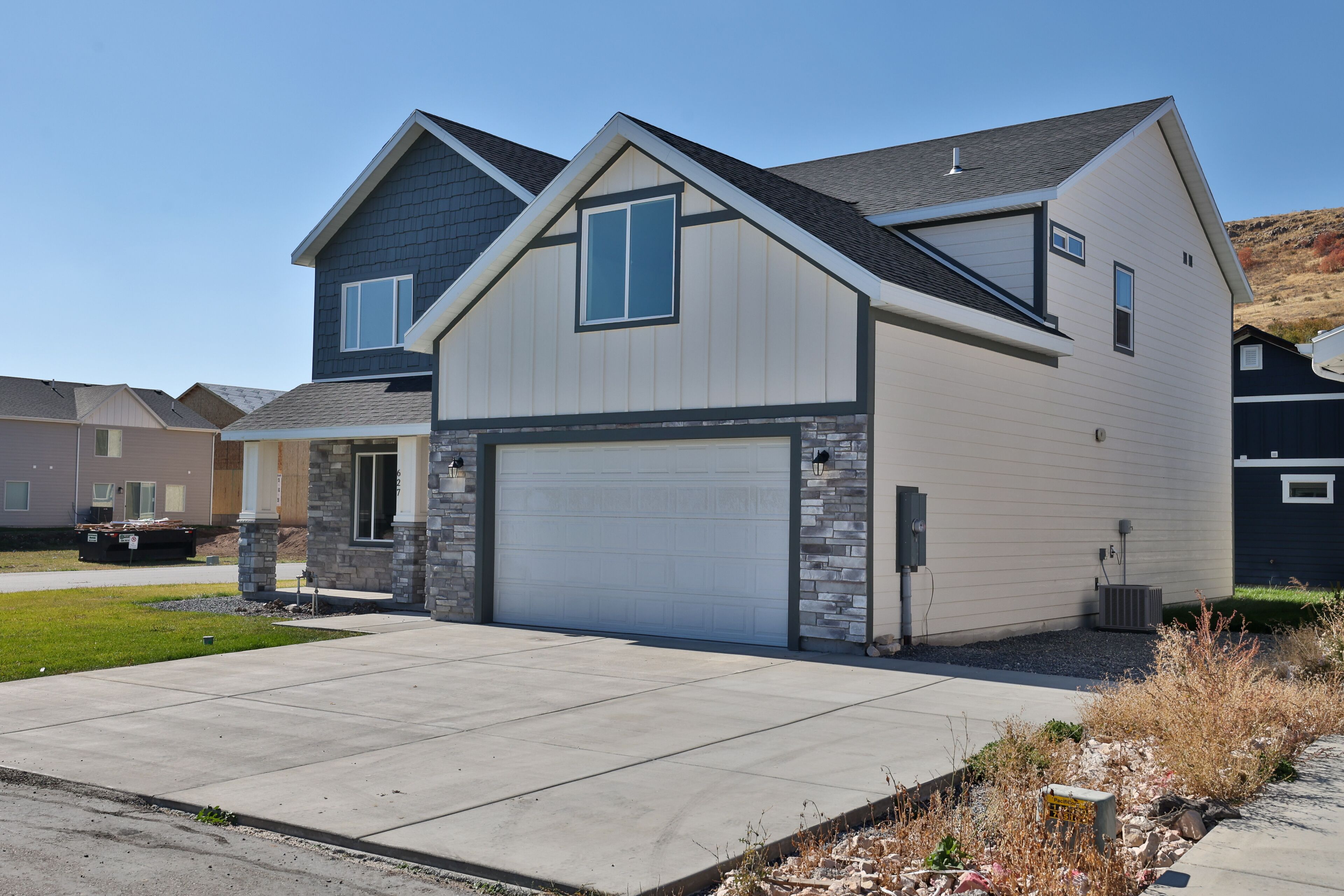 A modern two-story house with a garage, stone accents, and a clear driveway.