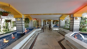 A hotel lobby with a central water feature, multiple seating areas, and indoor plants. - Benal Beach (Benalmádena)