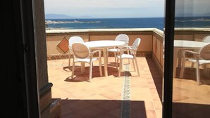 A balcony with a table and chairs, a tiled floor, and a view of the ocean. - Benal Beach (Benalmádena)