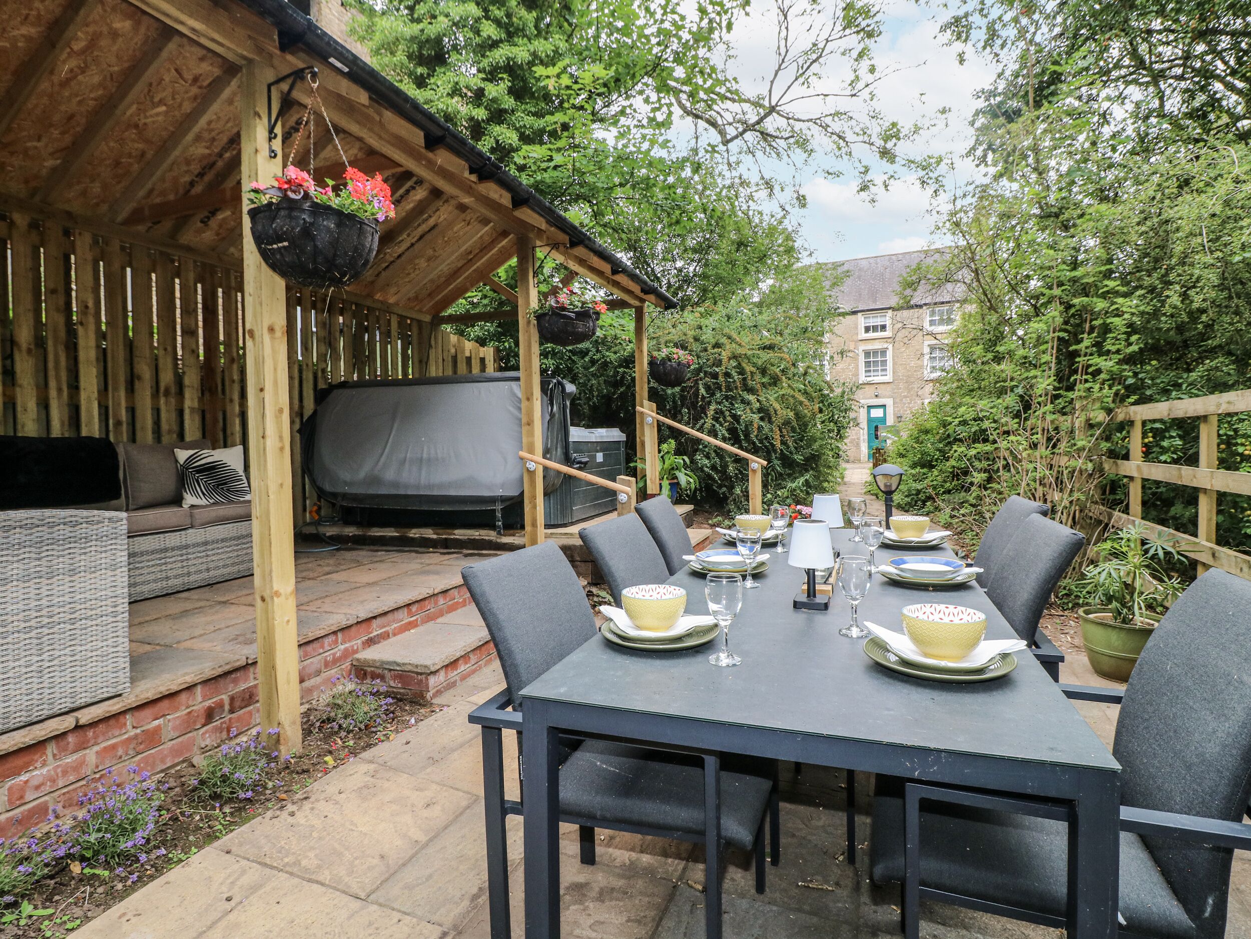 An outdoor patio with a covered seating area, a dining table set for four, and a garden view.