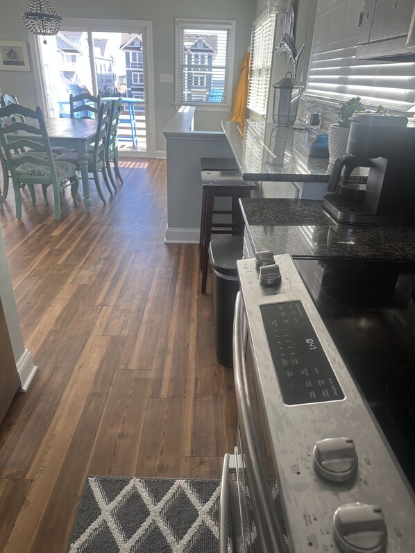 A kitchen with a stainless steel range, a coffee maker, and a window with blinds.