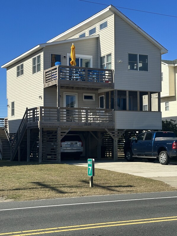 A two-story building with a balcony and a covered parking area. - Completely Renovated in 2022! Perfect Location! (Kill Devil Hills)