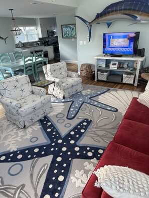 A modern living room with a starfish-patterned sofa, a red couch, and a large starfish rug.