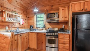 A wooden cabin kitchen with a stainless steel stove, oven, microwave, and refrigerator. - Pet-Friendly Mountain Log Cabin for Couples (Hot Springs)