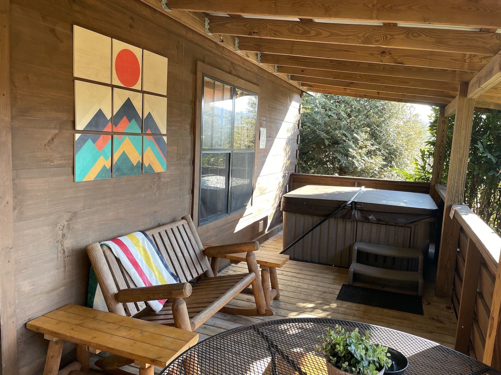 A wooden deck with a bench, a table, and a hot tub.