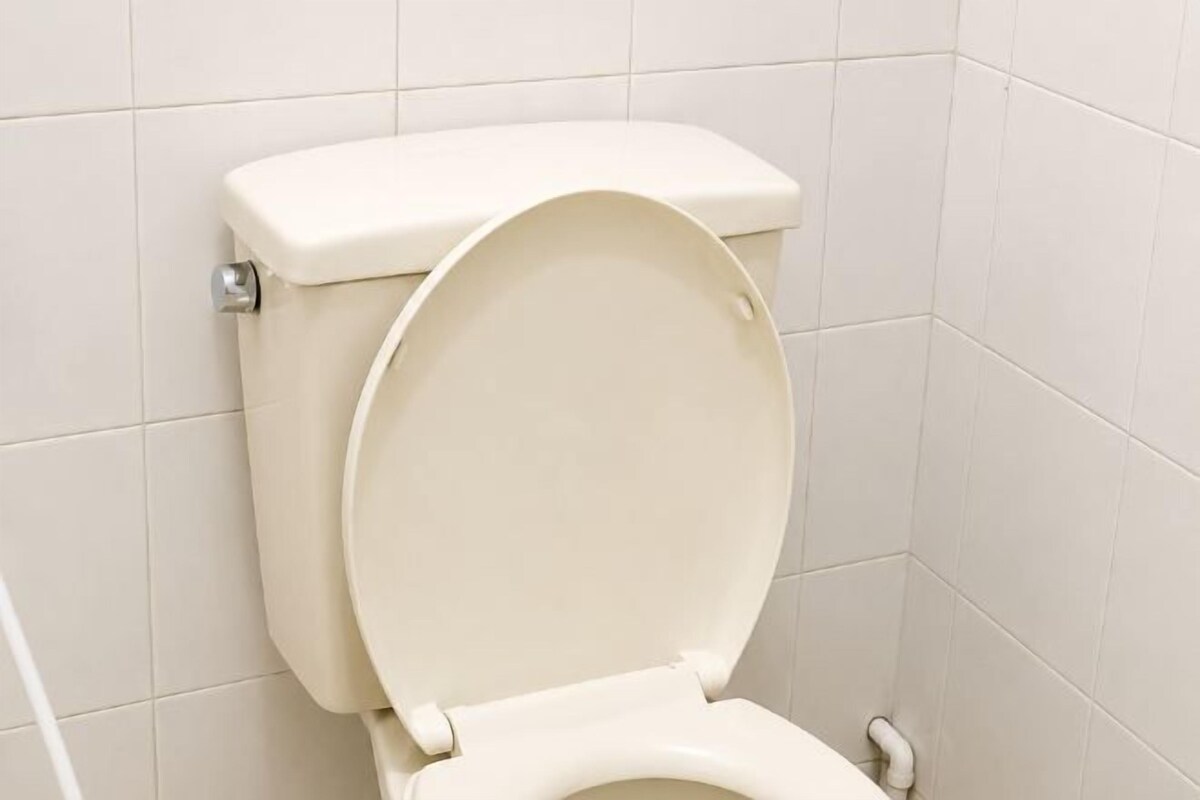 A toilet with a closed lid in a bathroom with white tiled walls.