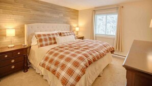 A bedroom with a wooden headboard, a bed with plaid bedding, bedside lamps, and a window with curtains. - Modern Townhome- Walk to Brewery (Woodstock)