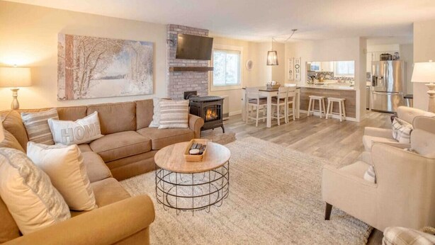 A spacious living room with a fireplace, a dining area, and a kitchen. - Modern Townhome- Walk to Brewery (Woodstock)