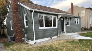 A single-story house with a brick chimney, a small porch, and a front yard with scattered leaves. - Charming Ranch style house across from Mercyhurst University (Erie)