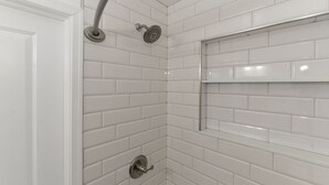 A corner shower with white subway tiles, a chrome showerhead, and a wall-mounted shelf. - Feng shui Philly Townhouse Unit w Rooftop (Philadelphia)