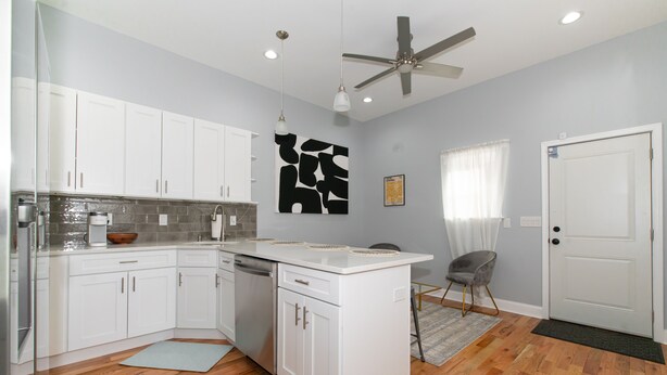 A modern kitchen with white cabinets, a central island, and a ceiling fan. - Feng shui Philly Townhouse Unit w Rooftop (Philadelphia)