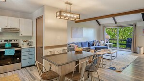 Una cocina moderna con una isla central, sillas de comedor y una lámpara colgante.