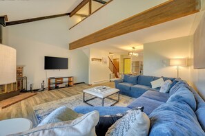 A spacious living room with a large sectional sofa, a coffee table, and a fireplace.