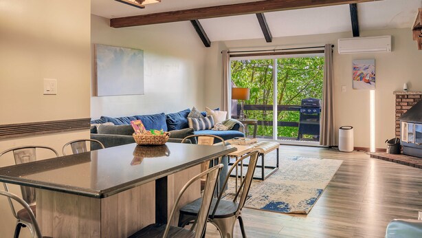 Una cocina moderna con una isla central, sillas de comedor y un amplio ventanal con vistas a una terraza.