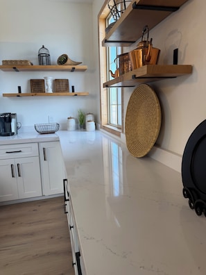 Eine moderne Küche mit weißen Schränken, einer Marmorarbeitsplatte und Holzböden.