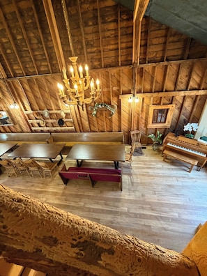 Ein rustikales Holzinterieur mit einer Chandelieber, Holzbänken, Tischen und einem Klavier.