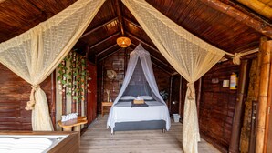 A wooden cabin with a bed under a canopy, a hot tub, and a wooden floor. - Glamping Mirador de Santa Fe  (Sopetrán)