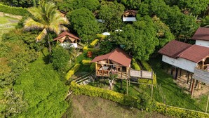 An aerial view of a resort with multiple bungalow-style structures surrounded by lush greenery. - Glamping Mirador de Santa Fe  (Sopetrán)