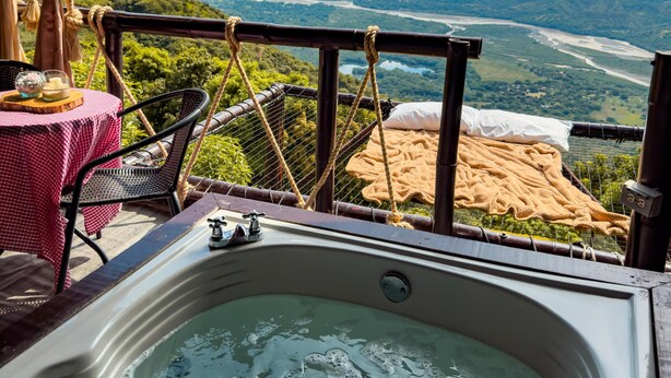 A hot tub with a view of a river and mountains. - Glamping Mirador de Santa Fe  (Sopetrán)