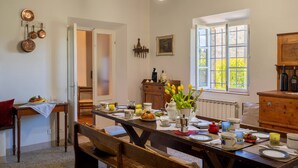 A dining area with a wooden table set for a meal, surrounded by chairs. There is a window with a view of greenery outside. - Villa in Gambassi with pool, A/C, village and restaurant at walking distance, (Gambassi Terme)