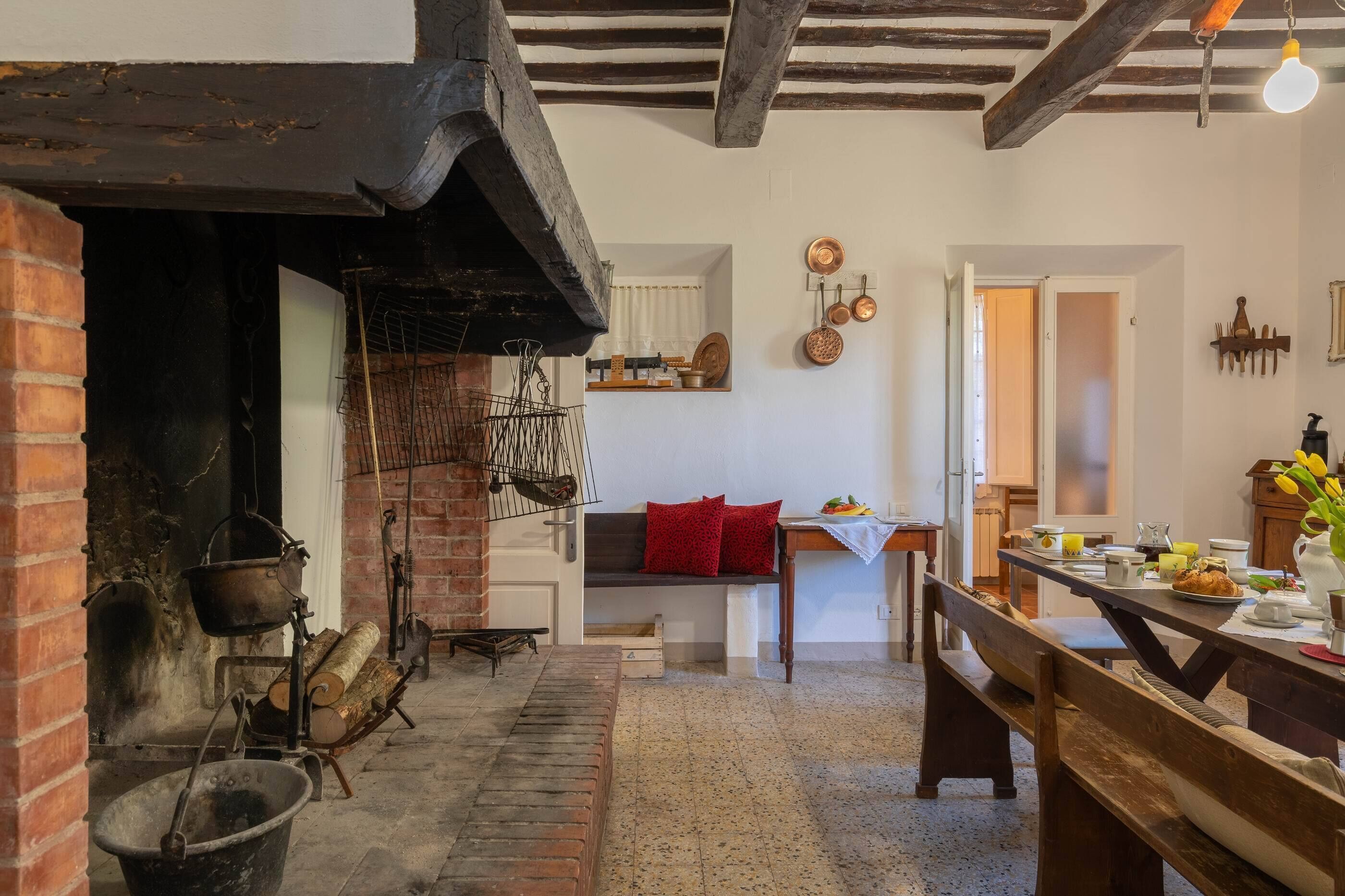 A rustic kitchen with exposed brick, wooden beams, and a traditional stove.