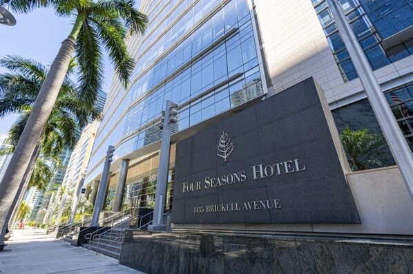 Het uiterlijk van het Four Seasons Hotel aan het Brickell Avenue 1435, met een moderne glazen gevel en palmbomen.