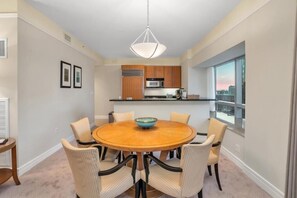 Een moderne eethoek met een ronde tafel, zes stoelen en een hanglamp.