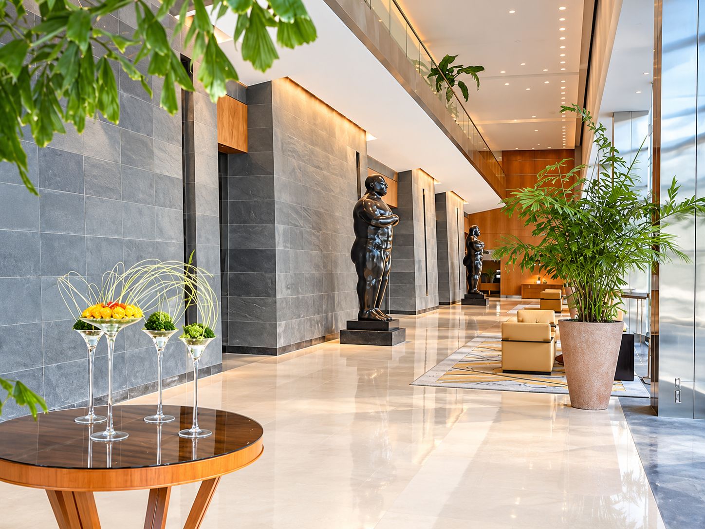 Een moderne lobby met een marmeren vloer, een receptiebalie en een grote potplant.