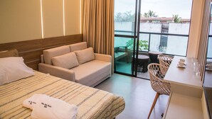 A hotel room with a bed, sofa, and a balcony with a table and chairs. - Villa del Porto (Ipojuca)