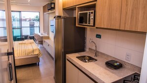 A compact kitchen with a refrigerator, microwave, sink, and a small countertop. - Villa del Porto (Ipojuca)