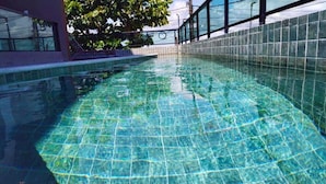 A swimming pool with clear water, surrounded by a tiled wall and a glass barrier. - Villa del Porto (Ipojuca)
