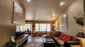Relax in this inviting living room with a large flat-screen TV, comfortable seating area, and stunning views of the outdoors.