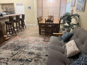 Relax in this open-plan living space with a dining area, featuring a sofa, area rug, and potted plant.