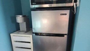 A compact kitchen with a stainless steel refrigerator, a microwave, and a coffee maker on a small white cabinet. - Tranquilo y Comodo. (Compton)