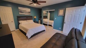 A bedroom with a bed, a ceiling fan, a dresser, a nightstand, and a door. - Tranquilo y Comodo. (Compton)