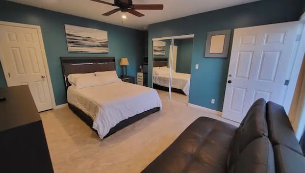 A bedroom with a bed, a ceiling fan, a dresser, a nightstand, and a door. - Tranquilo y Comodo. (Compton)