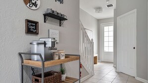 Eine Küchenzeile mit einer Kaffeemaschine, Regalen voller Gläser und einem Schild an der Wand.