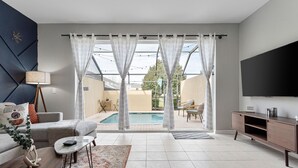 Ein modernes Wohnzimmer mit Pool, einer Couch, einem Couchtisch und einem Fernseher.