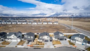A residential area with modern houses, a clear road, and a mountainous backdrop. - Home in American Fork - Lakeshore (Highland)
