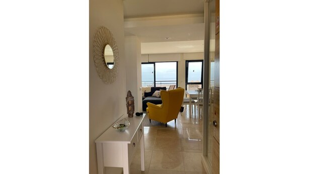 A modern living room with a yellow armchair, a white console table, and a decorative mirror. - Apartment La Verita, Caleta de Fuste (Castillo Caleta de Fuste)