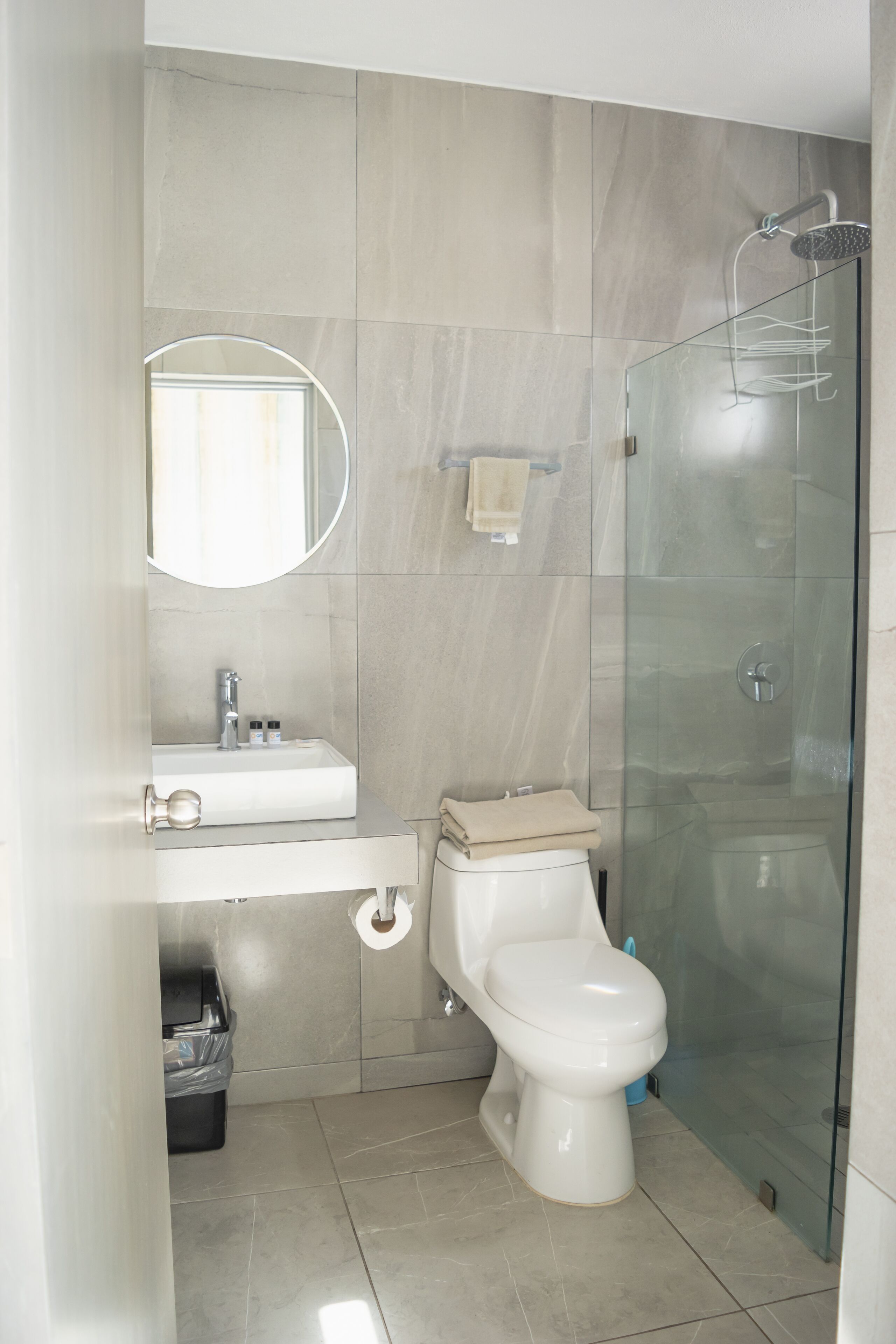 A bathroom with a glass-enclosed shower, a white sink, and a toilet.