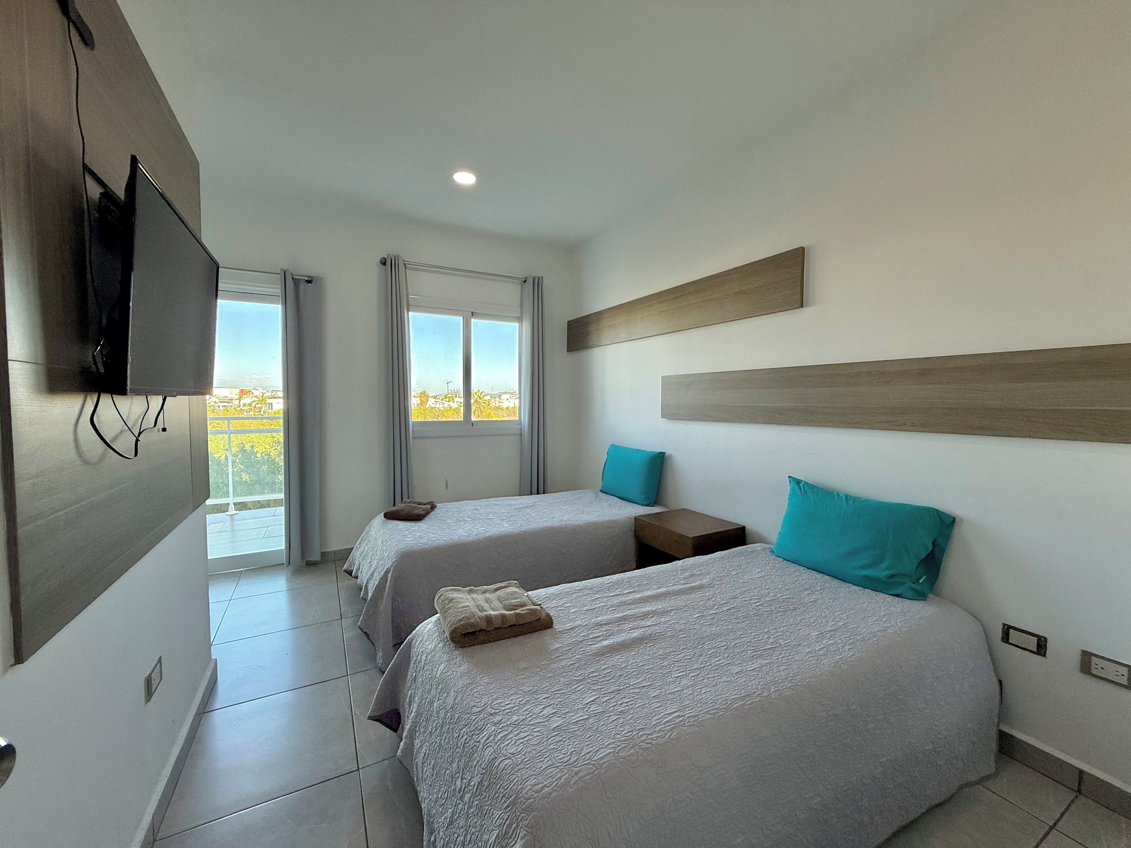 Une chambre d’hôtel avec deux lits, un téléviseur fixé au mur, une fenêtre donnant sur un paysage agréable et un luminaire au plafond.