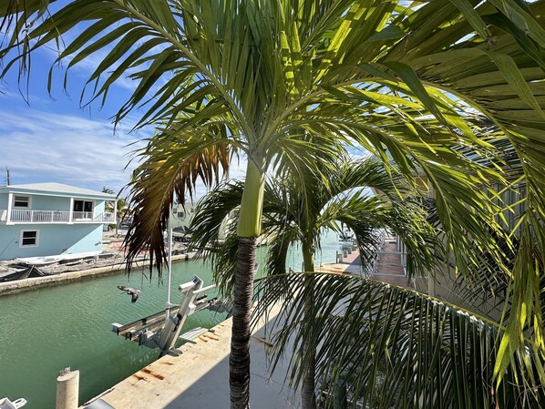 A marina with boats docked, a clear blue sky, and a building with a balcony.