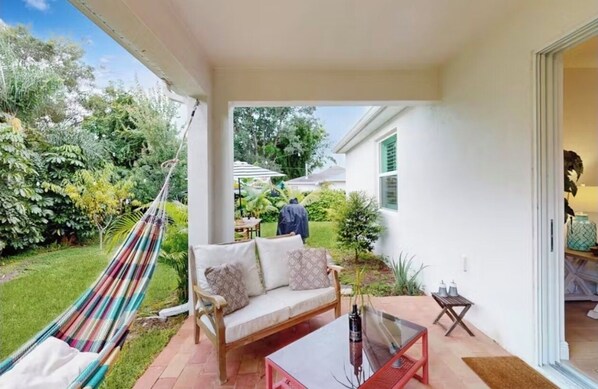 A patio with a hammock, a sofa, and a glass table. - Boaters Cove ~ 3 Car Garage Home (Sebastian)