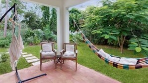 A patio with two cushioned chairs, a hammock, and a hanging chair. - Boaters Cove ~ 3 Car Garage Home (Sebastian)