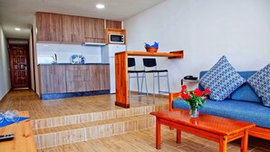 A modern kitchen with wooden cabinets, a microwave, and a dining area with a wooden table and chairs. - Tamaran (San Bartolomé de Tirajana)