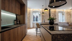 Una cocina moderna con armarios de madera, encimera de mármol e iluminación colgante.