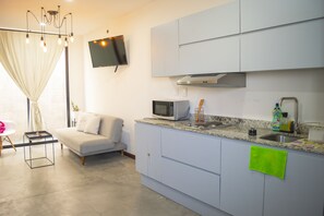 A modern kitchen with a flat-screen TV, a microwave, and a sink. - Soho Apartments (Mazatlán)